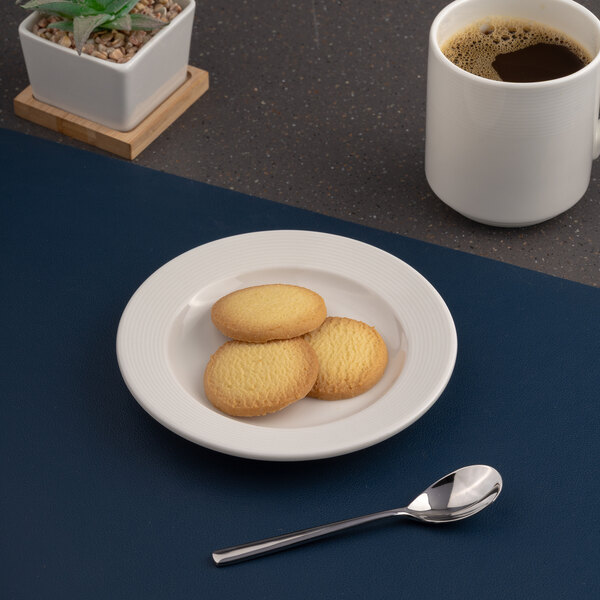 A white round embossed wide rim flat porcelain plate with three cookies on it.