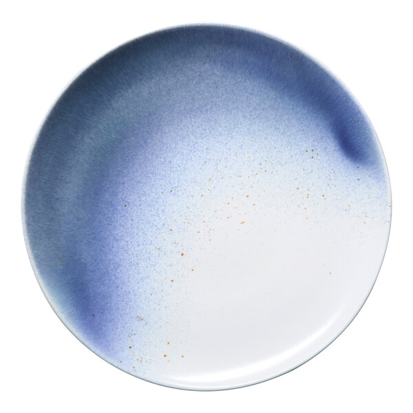 A round porcelain flat coupe plate with a blue and white ombre design and subtle speckled accents.