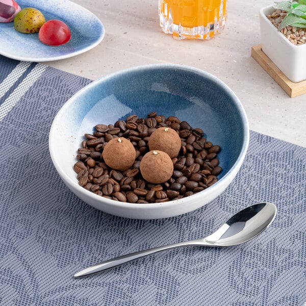 A blue and white ombre round porcelain coupe bowl filled with coffee beans and chocolate truffles.