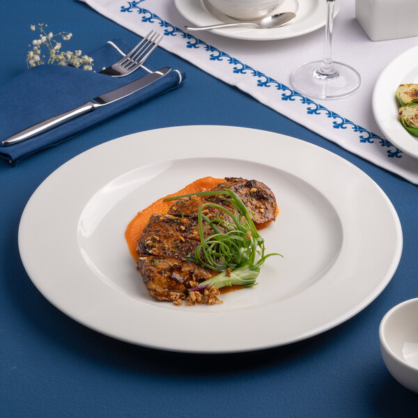 A white round porcelain plate with an embossed wide rim, featuring a gourmet food presentation.
