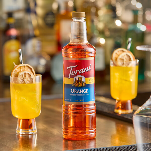 A 1-liter plastic bottle of Torani Orange flavoring syrup displayed on a bar counter.