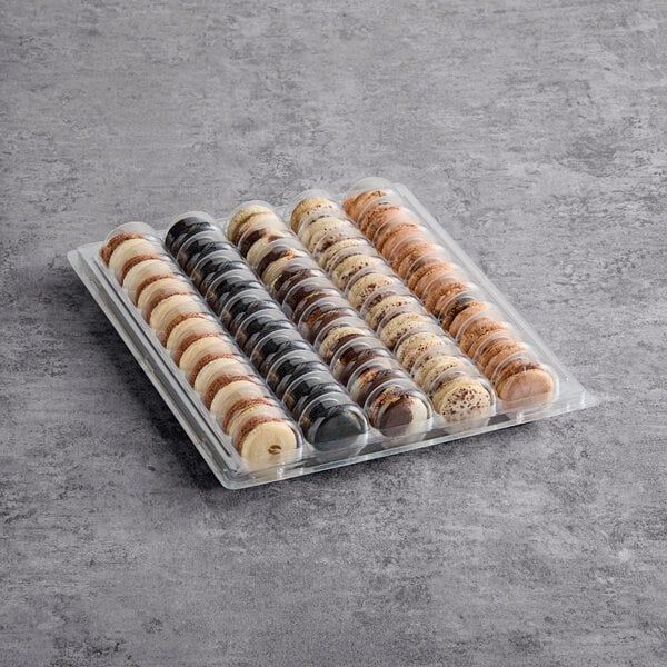 A plastic tray containing an assortment of coffee-flavored macarons arranged in rows.