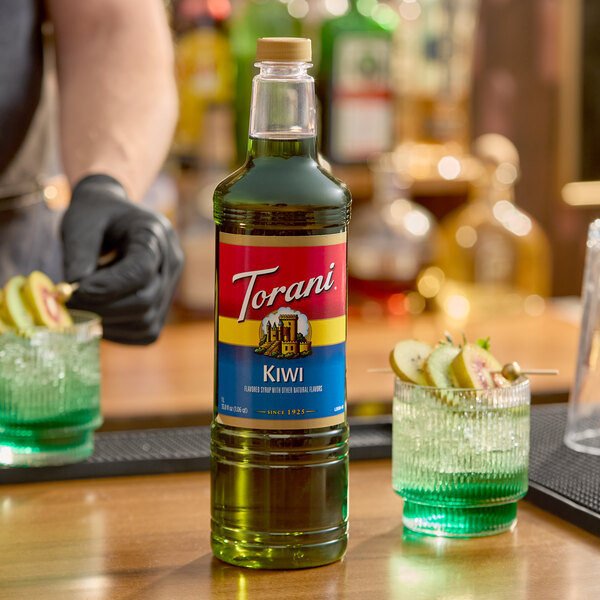 A 1-liter plastic bottle of Torani Kiwi flavoring syrup displayed on a bar counter.