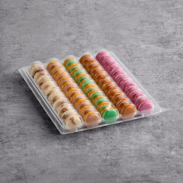 A clear plastic tray containing an assortment of colorful macarons in four different flavors.