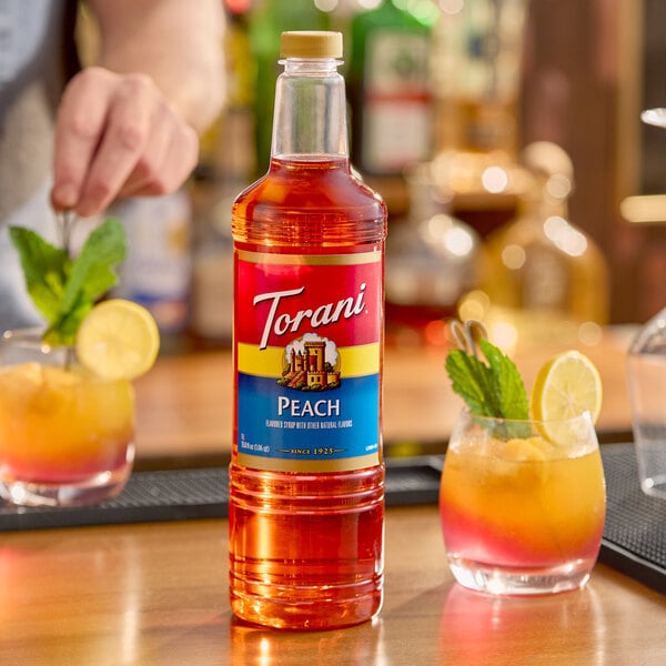 A 1-liter plastic bottle of Torani Peach flavoring and fruit syrup.