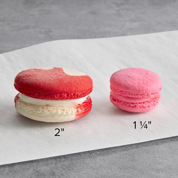 A pair of macarons in different sizes, one measuring 2 inches and the other 1 1/4 inches, displayed on a white surface.