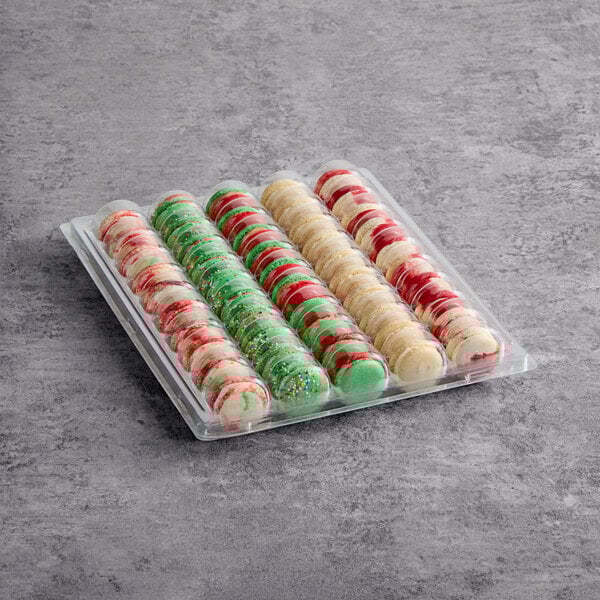 A plastic tray containing an assortment of colorful Christmas-themed macarons.