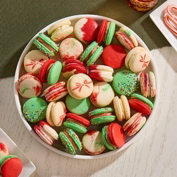 A plate of assorted Christmas-themed macarons in red, green, and white colors with festive decorations.