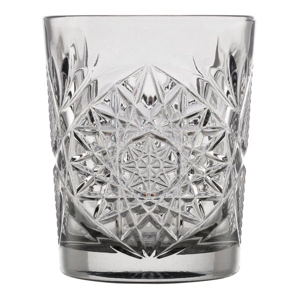 A clear glass tumbler with an intricate, starburst cut pattern design.