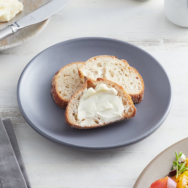 A small granite-colored satin matte porcelain coupe plate holding slices of bread, one with butter.
