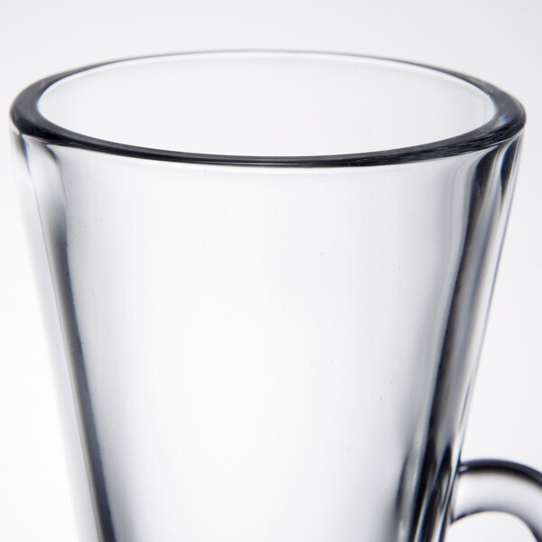 A clear glass coffee mug with a handle.