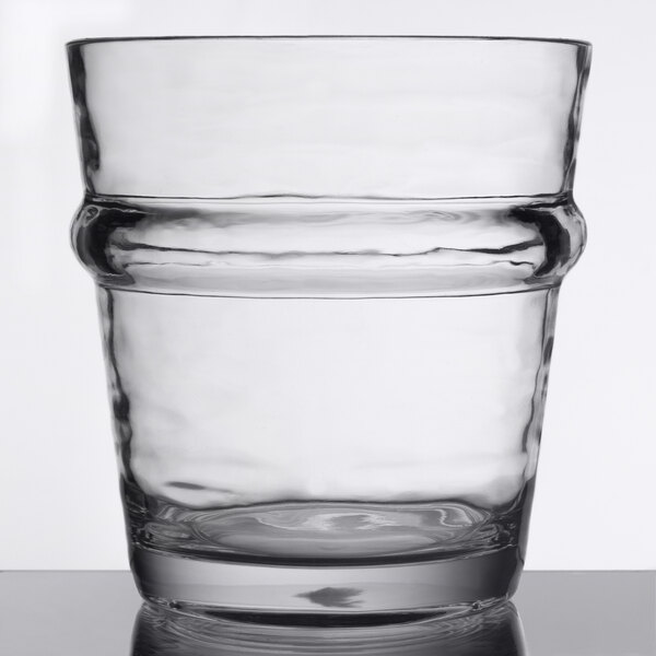 A clear, stackable 12 oz. plastic double rocks or old fashioned glass with a pronounced ridge around the middle.
