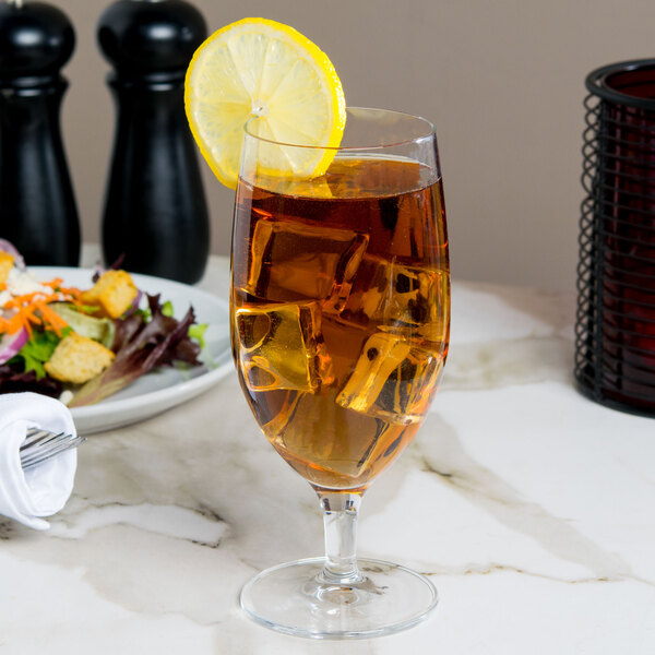 A clear goblet filled with iced tea and garnished with a lemon slice.