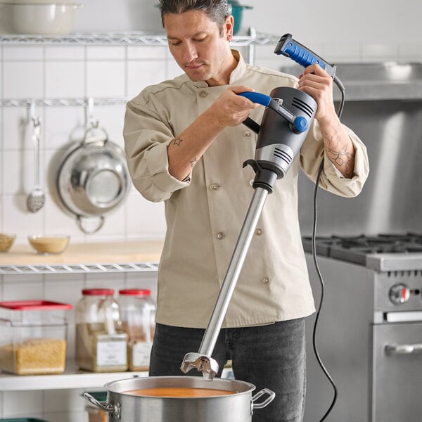 A chef using a Waring WSB700X Big Stik EvolutionX 21-inch electric variable-speed heavy-duty immersion blender in a commercial kitchen.