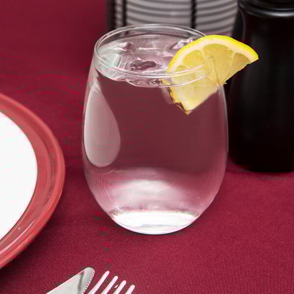 A clear 15 oz. stemless wine glass filled with water and ice, garnished with a lemon wedge.