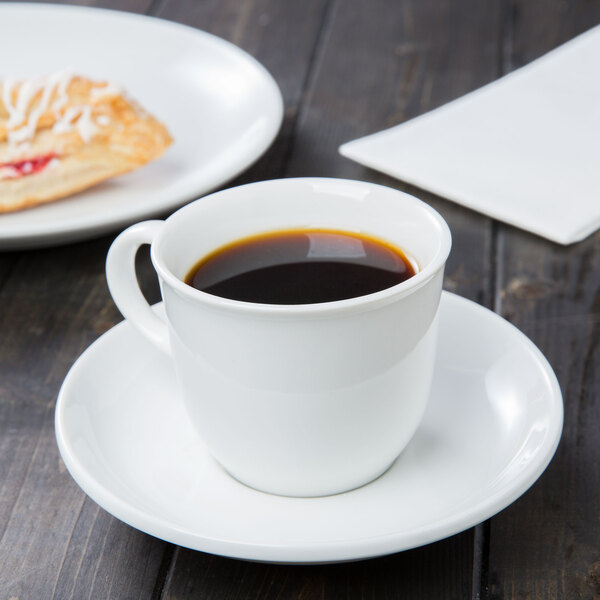 A white porcelain tea saucer with a matching cup filled with black coffee.