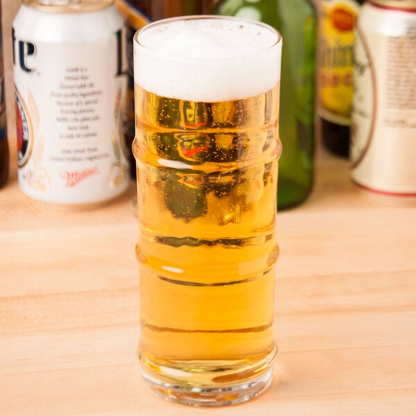 A clear Libbey 16 oz. specialty cooler glass filled with light beer and topped with foam.