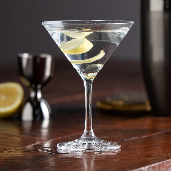 A clear Spiegelau Perfect Serve 5.5 oz. martini glass filled with a cocktail and garnished with a lemon twist.