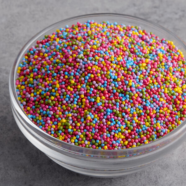 A glass bowl filled with colorful all-natural rainbow nonpareils.