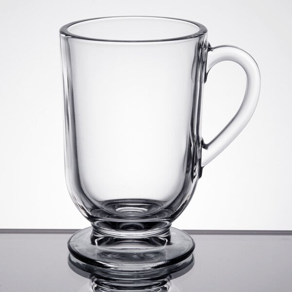 A clear 10.5 oz. glass coffee mug with a handle and a pedestal base.