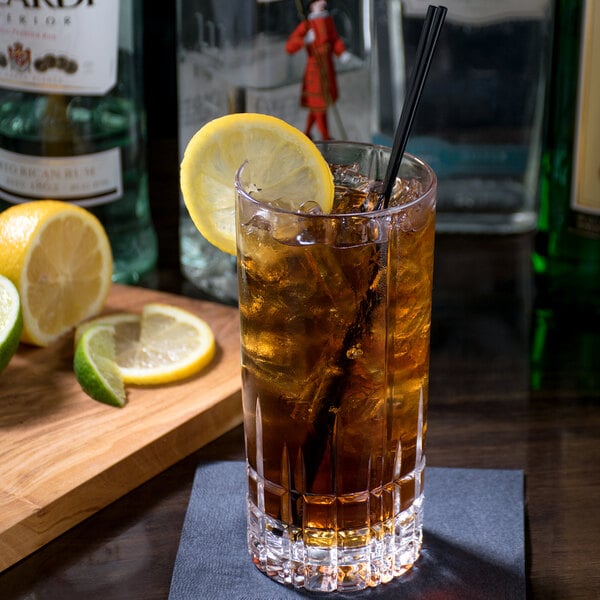 A clear, faceted 11.75 oz. longdrink or Collins glass filled with a dark beverage, ice, a lemon wheel garnish, and two black straws.