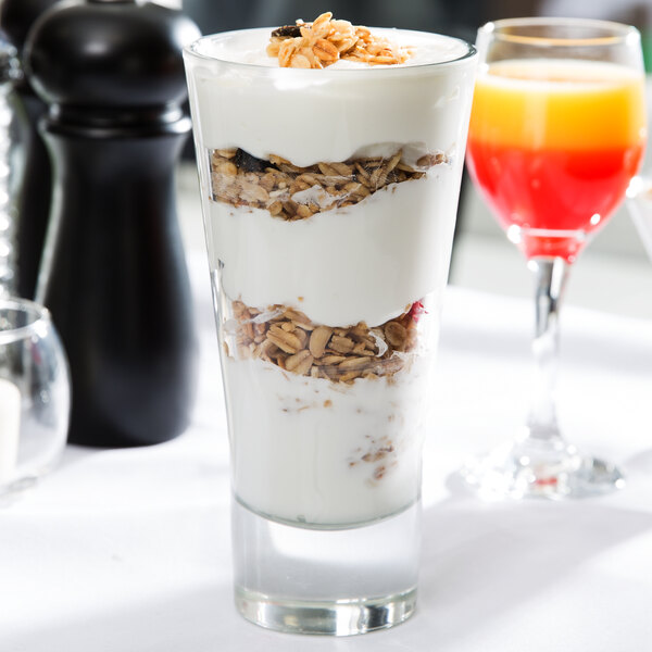 A tall, clear glass filled with layers of yogurt and granola.