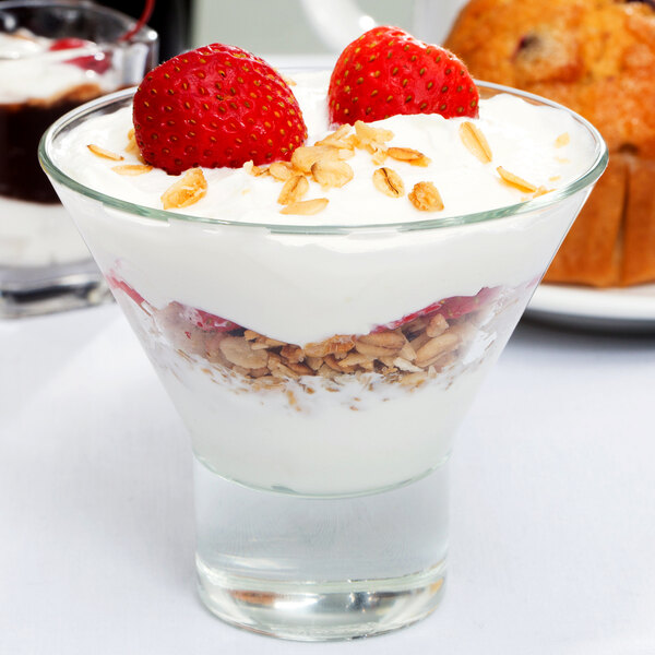 A clear Libbey Series V 7.6 oz. martini glass filled with layers of yogurt, granola, and strawberries.