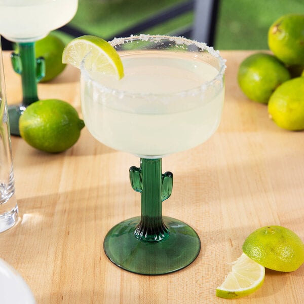 A 12 oz. margarita glass with a green cactus-shaped stem, filled with a margarita and garnished with a lime wedge.