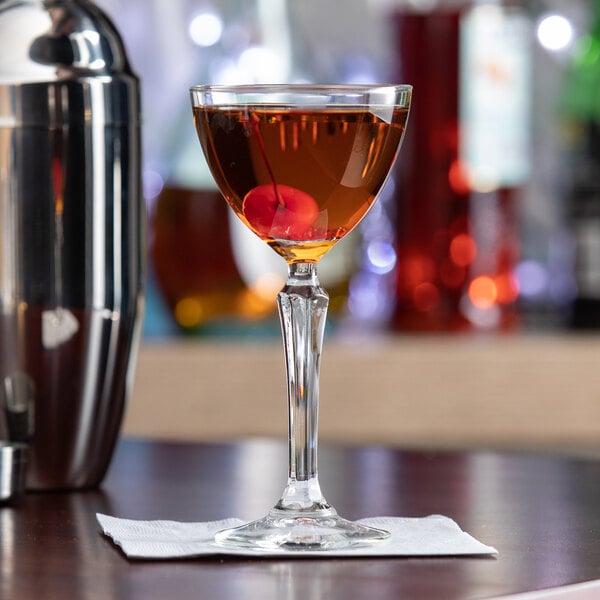 A clear Libbey Speakeasy 4.75 oz. Nick and Nora glass filled with a cocktail and garnished with a cherry.