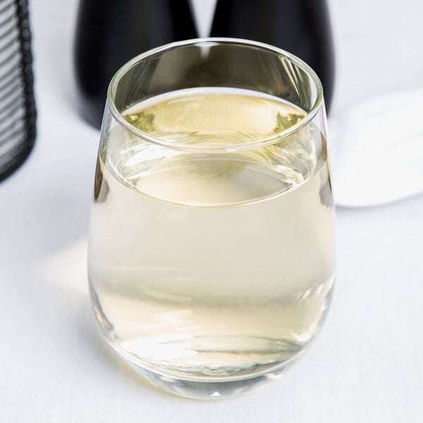 A clear, stemless white wine glass with a capacity of 15.25 ounces, partially filled with white wine.