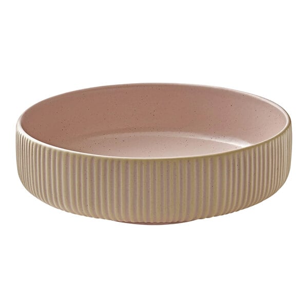 A round, ribbed ceramic bowl with a pink interior and beige exterior.
