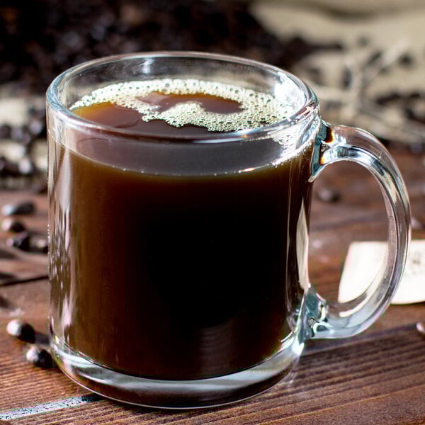 A clear glass mug filled with black coffee.