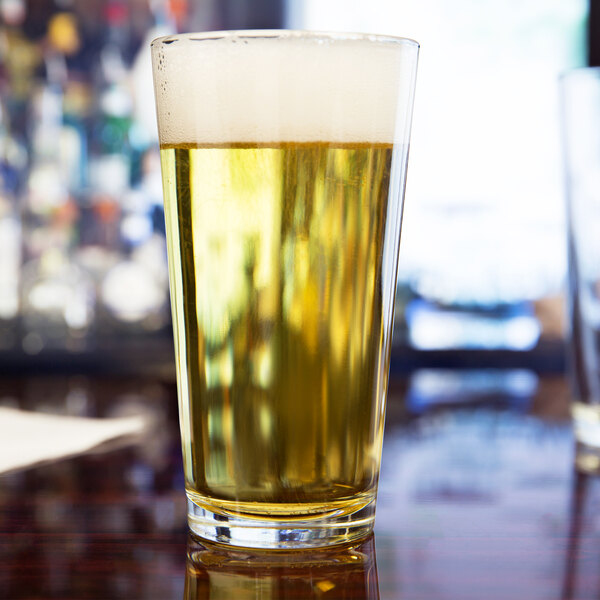 A clear 16 oz. tall mixing or pint glass filled with light beer and topped with foam.