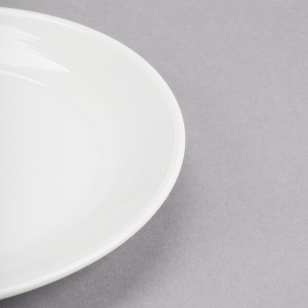 A white round porcelain coupe plate on a gray background.
