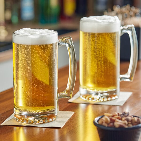 A large clear glass beer mug filled with light beer and topped with foam, placed on a coaster.