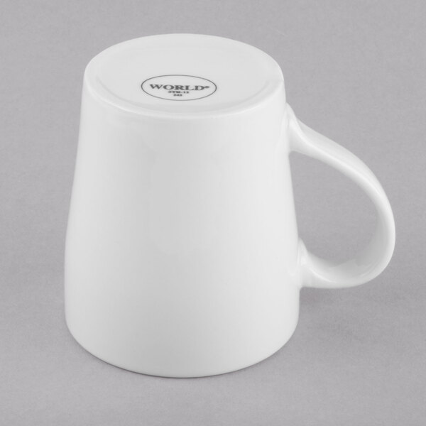 A plain white porcelain mug turned upside down on a gray surface.