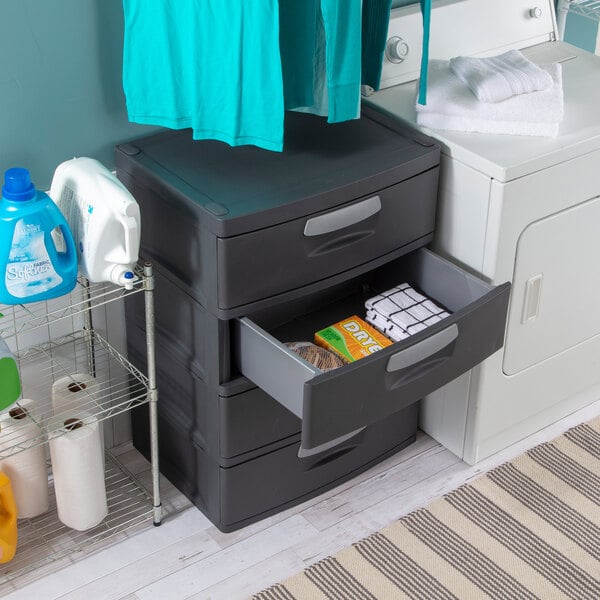 A flat gray four-drawer plastic storage cabinet placed in a laundry room setting.