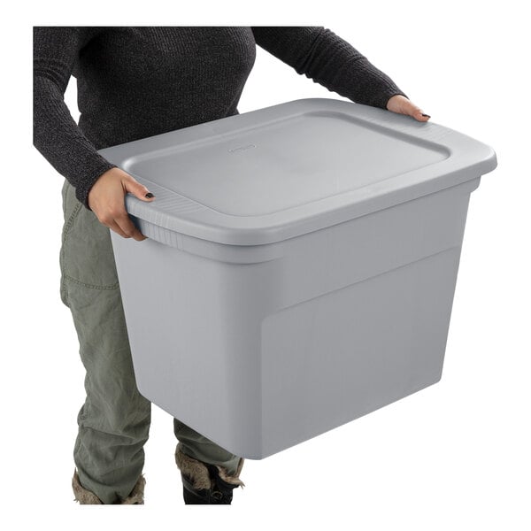 A large cement gray plastic storage tote with a lid being held by a person.