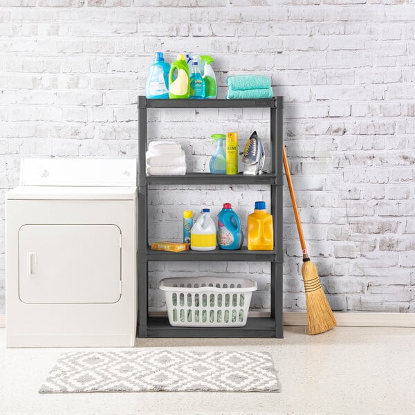 A gray four-shelf storage unit holding various laundry and cleaning supplies, placed next to a dryer in a laundry room.