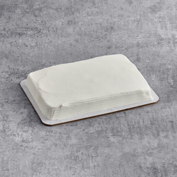 A rectangular yellow cake with smooth white buttercreme icing on a cardboard base.