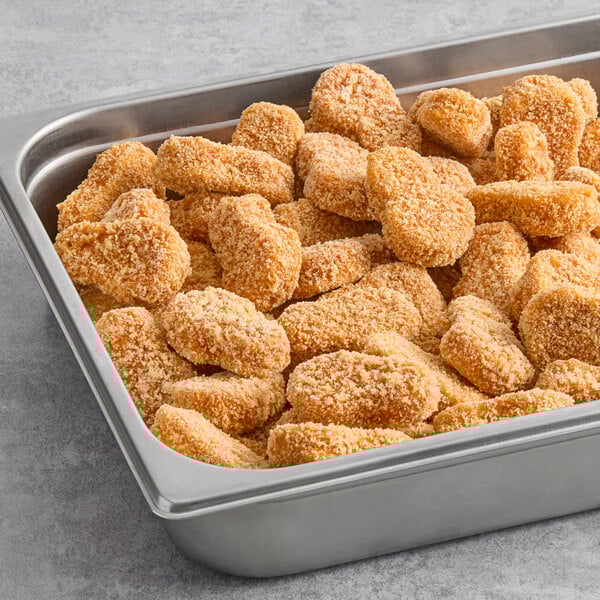 A stainless steel tray filled with breaded plant-based vegan buffalo wings.