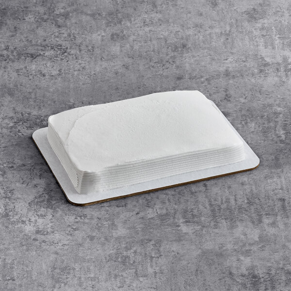 A rectangular chocolate cake with smooth white whipped icing on a cake board.
