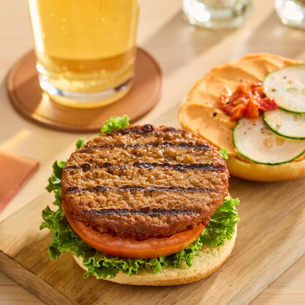 A plant-based vegetarian burger patty served on a bun with lettuce, tomato, cucumber slices, and sauce.