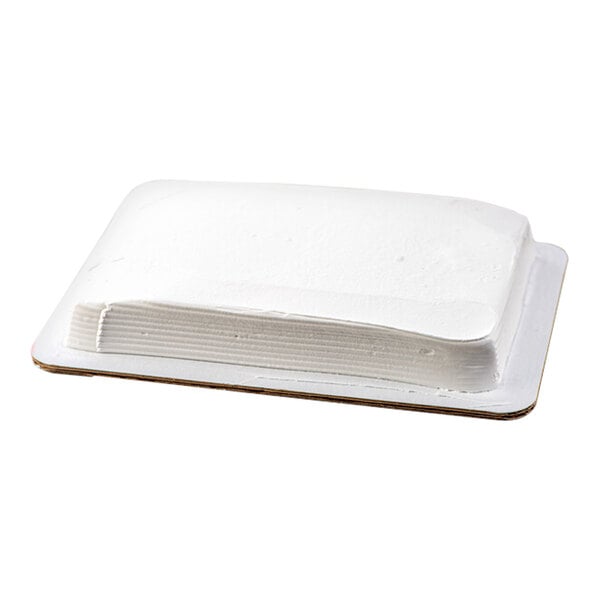 A rectangular yellow cake with white whipped icing on a cardboard base.