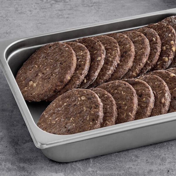 A stainless steel tray filled with several plant-based vegetarian spicy black bean burger patties.