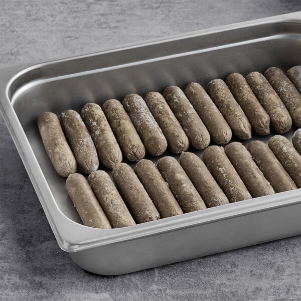 A stainless steel tray filled with frozen plant-based vegetarian breakfast sausage links.