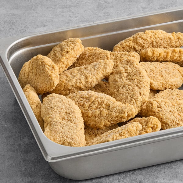 A stainless steel tray filled with breaded plant-based vegan chik'n tenders.