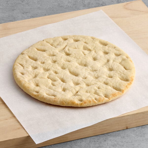 A round, par-baked pizza crust made with 00 flour, approximately 12 inches in diameter, placed on parchment paper.