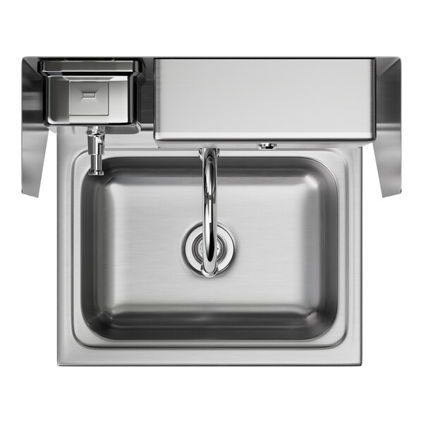 A stainless steel hands-free hand sink with a knee-operated valve, paper towel dispenser, and soap dispenser.