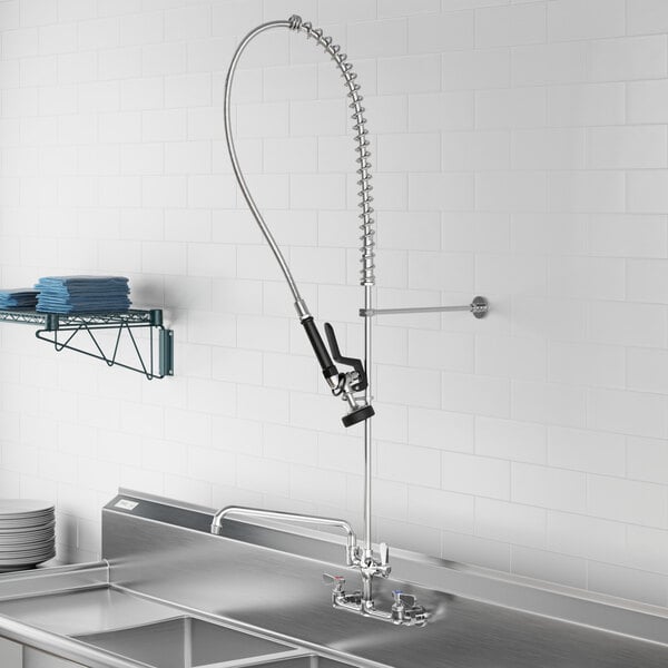 A commercial wall-mounted pre-rinse faucet with an 8-inch center and a 12-inch add-on faucet, installed above a stainless steel sink.